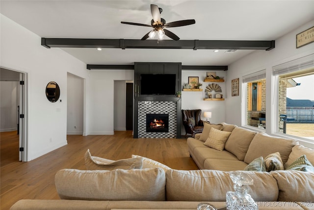 living room with beamed ceiling, a fireplace, wood finished floors, and baseboards