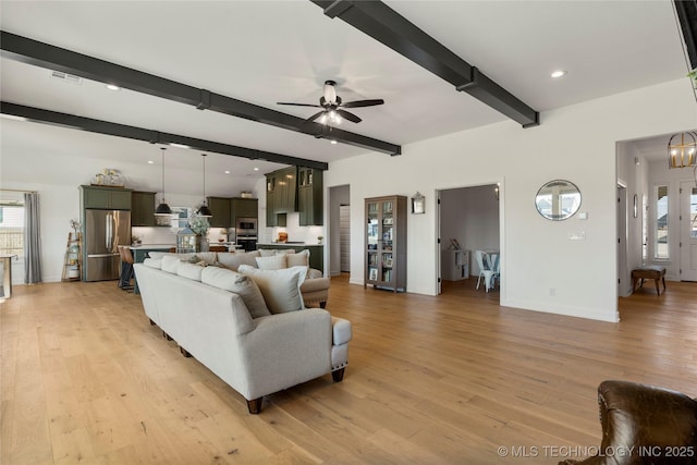 living area featuring light wood-style flooring, ceiling fan with notable chandelier, visible vents, baseboards, and beam ceiling