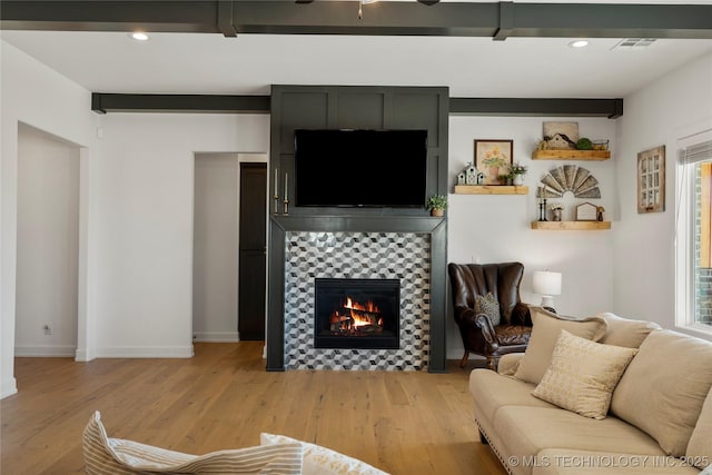 living area with recessed lighting, visible vents, a tiled fireplace, and light wood-style flooring