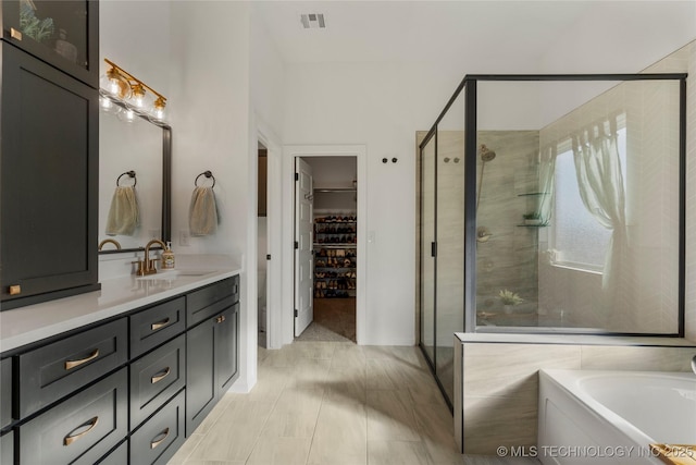 bathroom featuring a stall shower, visible vents, a walk in closet, and vanity