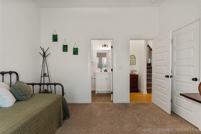 carpeted bedroom featuring ensuite bathroom and baseboards