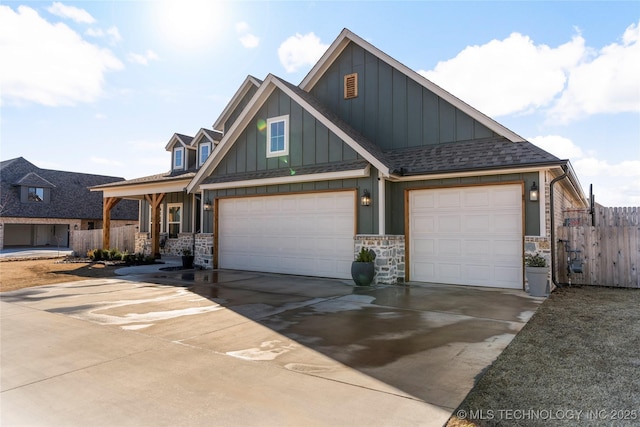 craftsman house with fence, concrete driveway, stone siding, roof with shingles, and board and batten siding