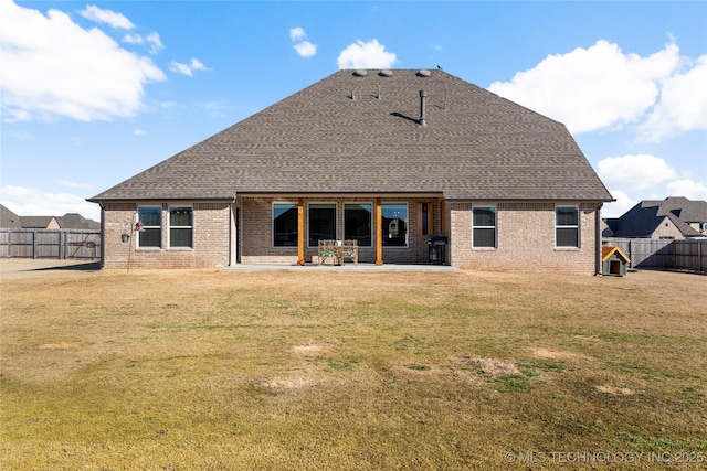 back of property with a yard, roof with shingles, a patio area, and a fenced backyard