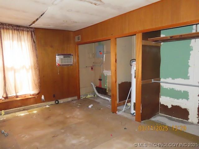 unfurnished room featuring visible vents, wood walls, and an AC wall unit