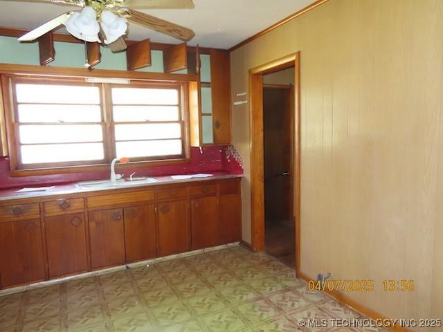 kitchen featuring light floors, light countertops, a sink, brown cabinetry, and ceiling fan