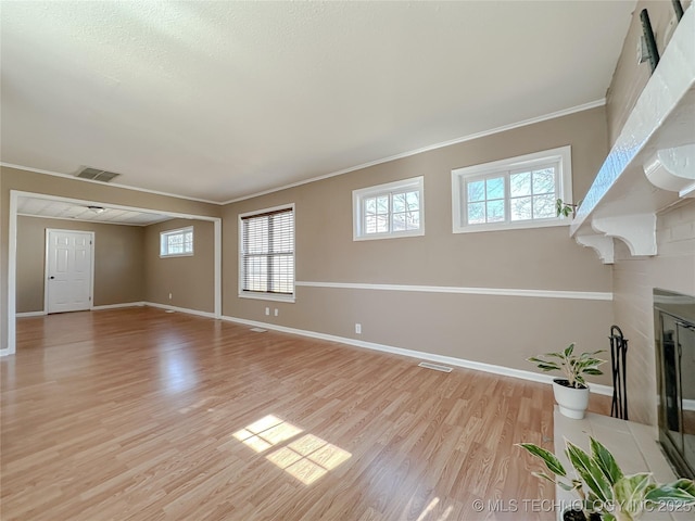 unfurnished living room with light wood-type flooring, visible vents, a fireplace, and baseboards