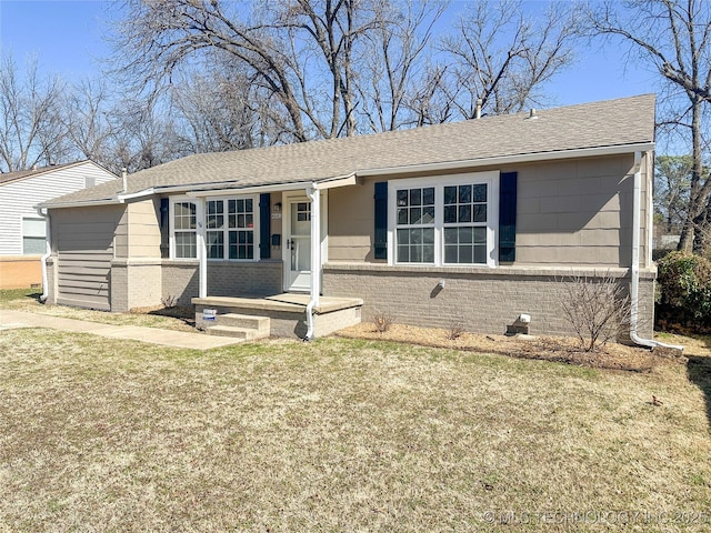 ranch-style home featuring roof with shingles, a front lawn, and brick siding