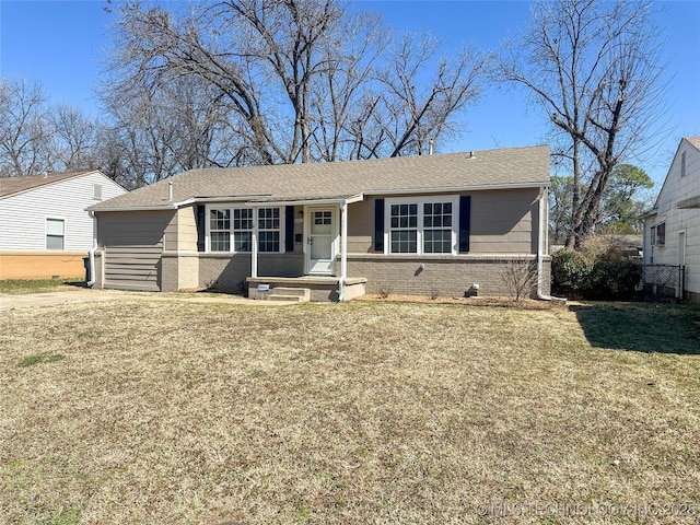 ranch-style house with a shingled roof, a front lawn, and brick siding