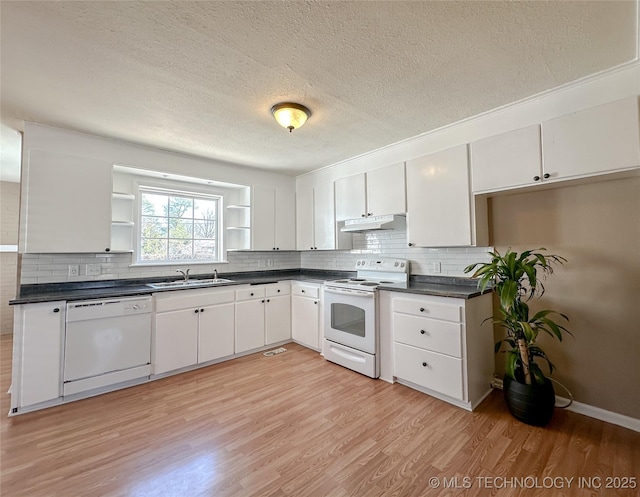 kitchen with under cabinet range hood, white appliances, a sink, open shelves, and dark countertops