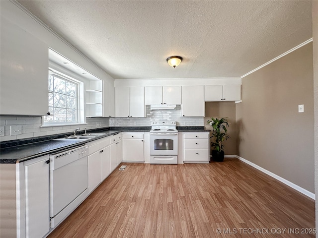 kitchen with under cabinet range hood, white appliances, a sink, white cabinets, and dark countertops