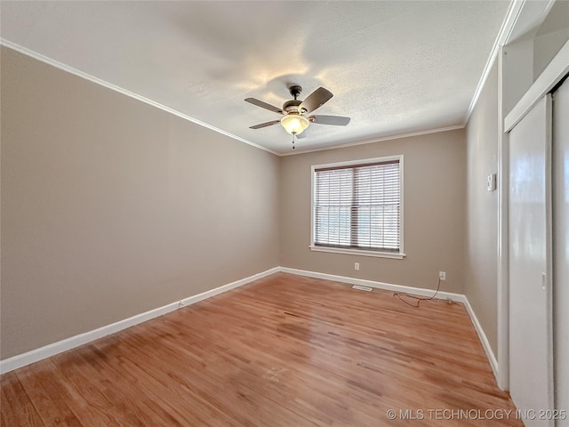 unfurnished bedroom featuring a closet, ornamental molding, light wood-style floors, a textured ceiling, and baseboards