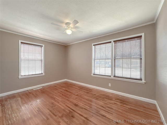 spare room with crown molding, visible vents, light wood-style flooring, ceiling fan, and baseboards