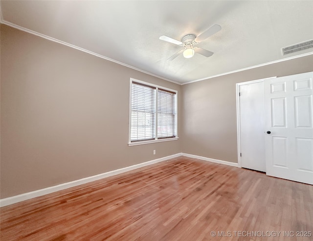 unfurnished bedroom with baseboards, visible vents, ceiling fan, crown molding, and light wood-type flooring