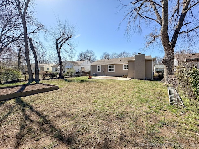 rear view of property featuring a patio, a yard, a chimney, and stucco siding