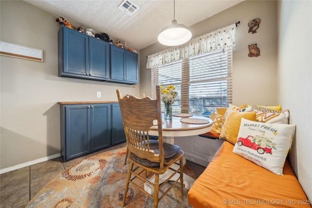 dining area with a textured ceiling, tile patterned flooring, visible vents, and baseboards