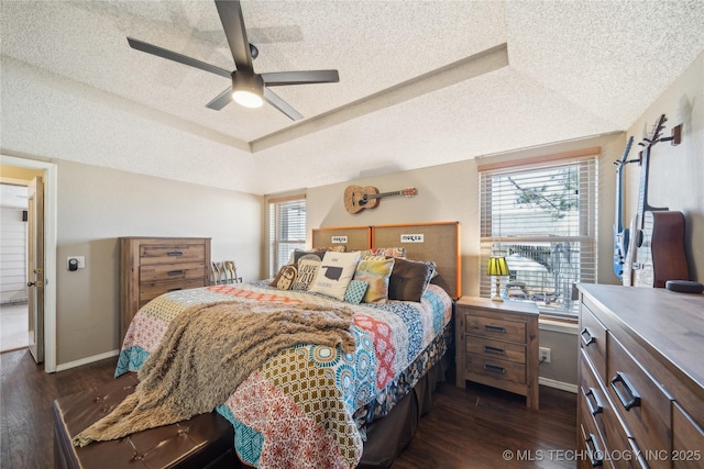 bedroom featuring dark wood-style floors, a raised ceiling, a textured ceiling, and baseboards