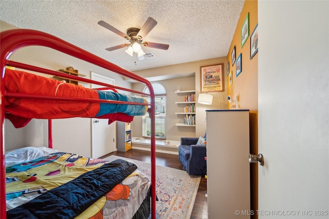 bedroom featuring visible vents, ceiling fan, a textured ceiling, and wood finished floors