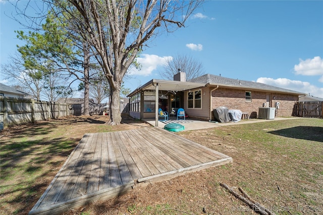 back of house with brick siding, a chimney, a lawn, cooling unit, and a fenced backyard