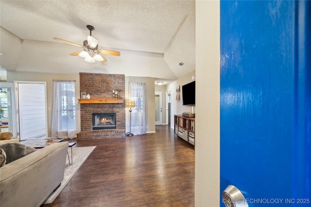 living room with visible vents, ceiling fan, wood finished floors, a textured ceiling, and a fireplace