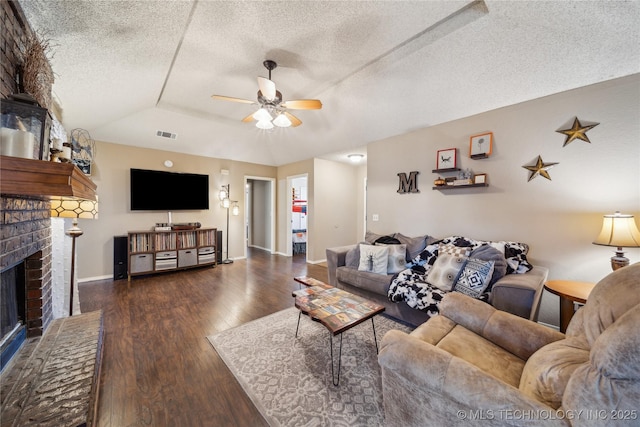 living room featuring a brick fireplace, ceiling fan, a textured ceiling, wood finished floors, and baseboards