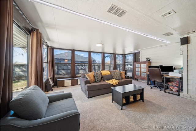 living room with a wealth of natural light, carpet flooring, and visible vents