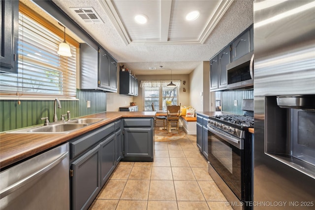 kitchen featuring light tile patterned flooring, a sink, visible vents, hanging light fixtures, and appliances with stainless steel finishes