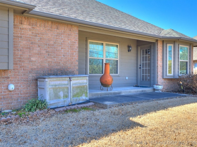 property entrance with brick siding and roof with shingles