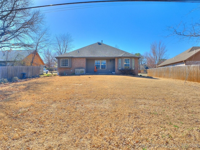 back of house with a yard, brick siding, and fence