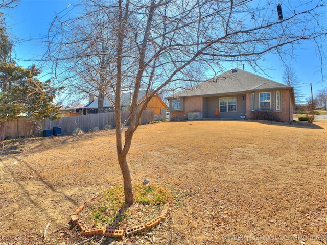 view of front of house featuring roof with shingles, brick siding, a front lawn, and fence