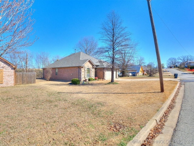 view of home's exterior featuring a yard, brick siding, fence, and driveway