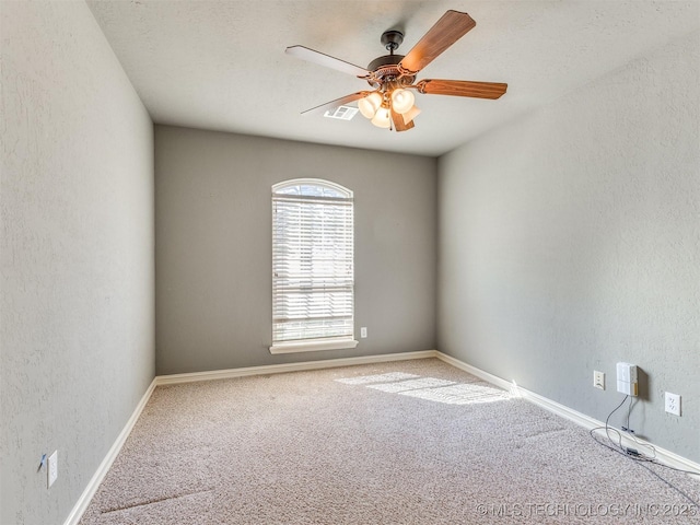 unfurnished room featuring a textured wall, carpet, visible vents, and a ceiling fan