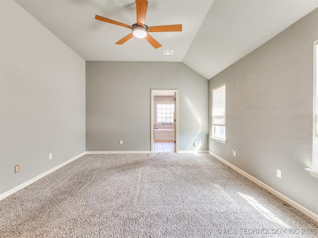 carpeted spare room with lofted ceiling, baseboards, visible vents, and a ceiling fan