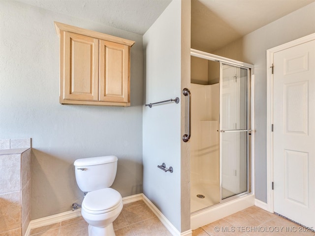 bathroom featuring toilet, a shower stall, baseboards, and tile patterned floors