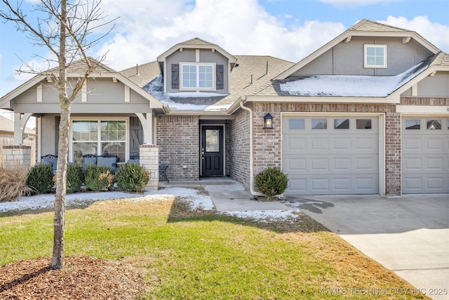 view of front of home with driveway, a shingled roof, a front lawn, and brick siding