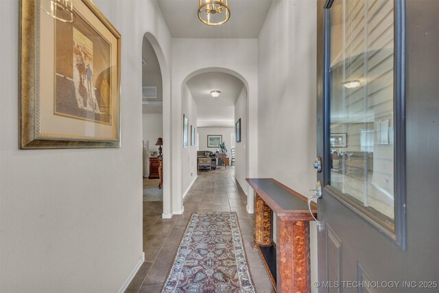 3838 E 144th St S, Bixby, OK 74008 - hallway with arched walkways, dark tile patterned flooring, and a chandelier