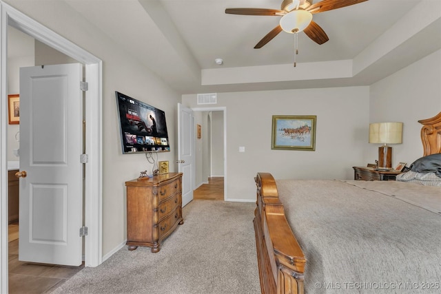 bedroom with baseboards, visible vents, a tray ceiling, and light colored carpet