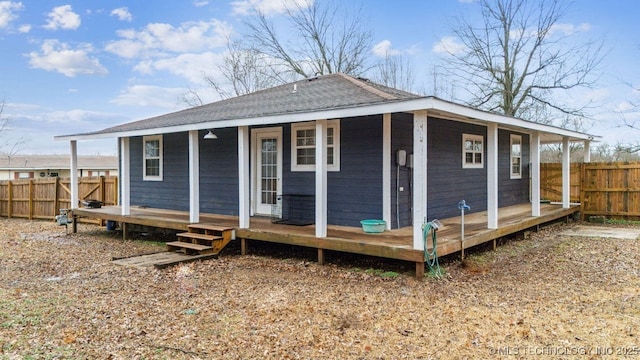 rear view of house with a porch, roof with shingles, and fence