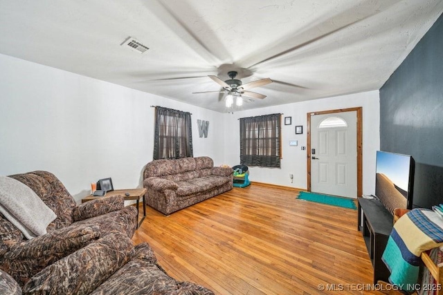 living area featuring baseboards, visible vents, ceiling fan, and light wood finished floors