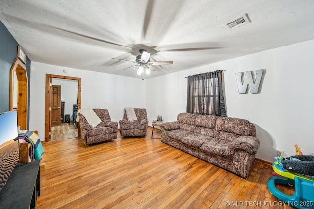 living room featuring hardwood / wood-style flooring, visible vents, and a ceiling fan