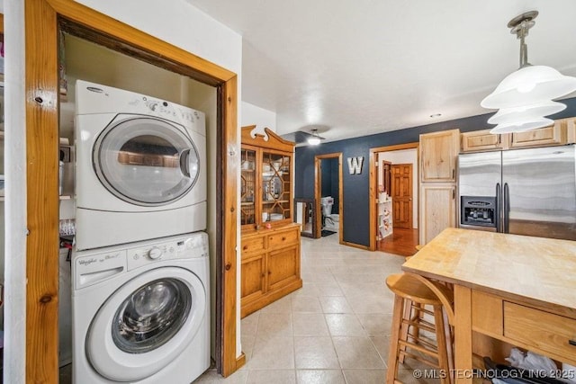 clothes washing area with light tile patterned floors, laundry area, and stacked washer and clothes dryer