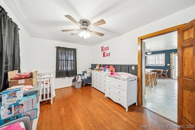 bedroom with hardwood / wood-style floors, visible vents, and a ceiling fan