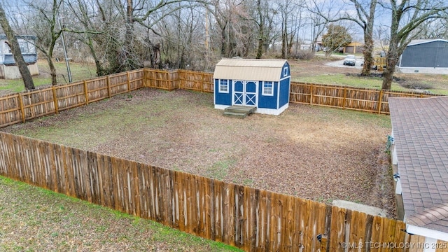 view of yard with a storage shed, a fenced backyard, and an outbuilding