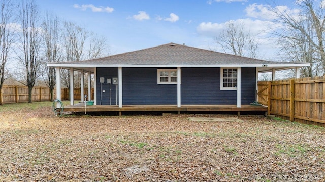 back of house with roof with shingles, an outdoor structure, and a fenced backyard