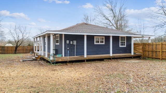 rear view of property featuring a shingled roof and fence