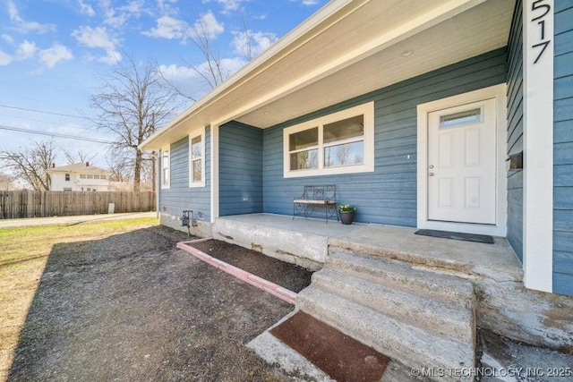 doorway to property featuring covered porch and fence