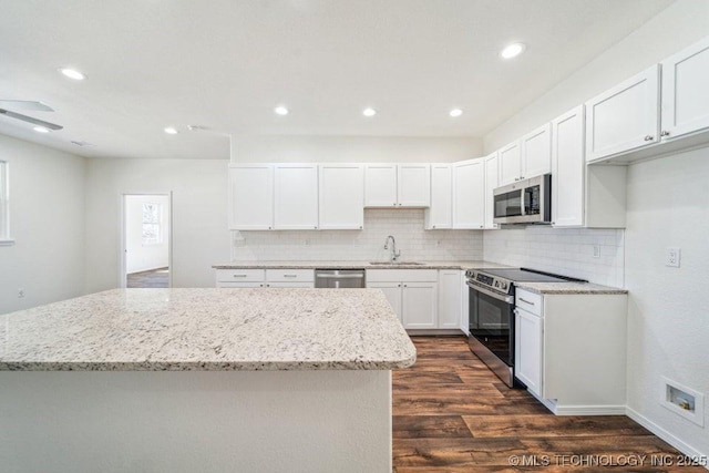 517 W Clyde Ave, Vinita, OK 74301 - kitchen with appliances with stainless steel finishes, dark wood finished floors, a sink, a kitchen island, and decorative backsplash