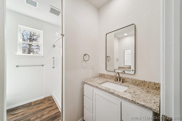 full bathroom with wood finished floors, visible vents, vanity, and a stall shower