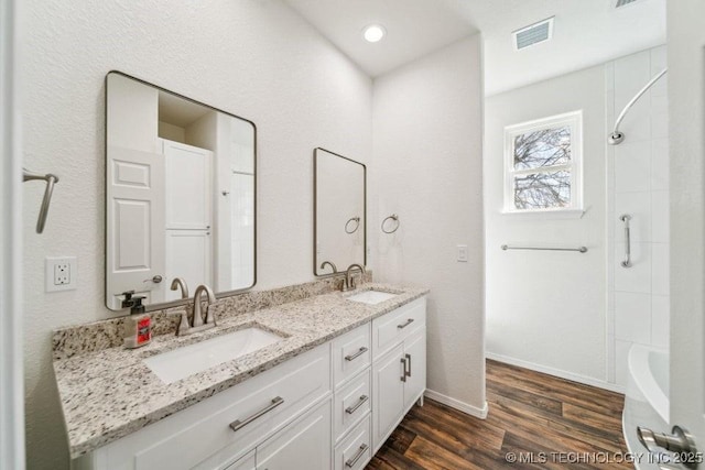 bathroom with visible vents, wood finished floors, double vanity, and a sink