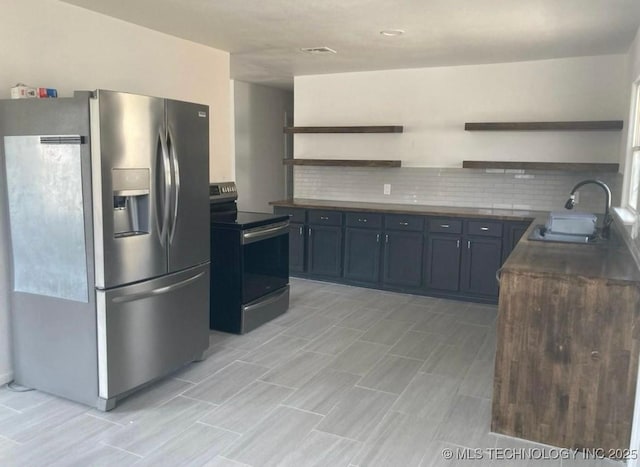 kitchen with dark countertops, appliances with stainless steel finishes, open shelves, and a sink