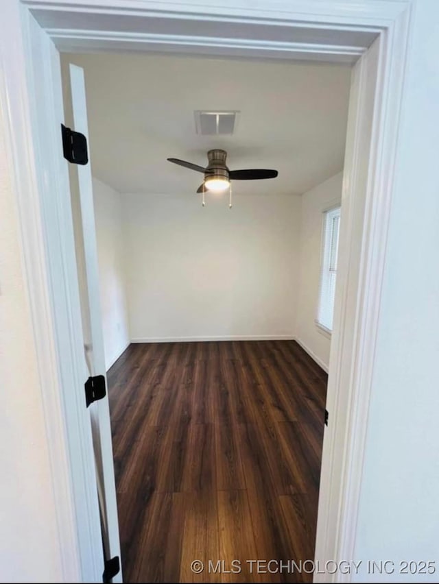 spare room featuring dark wood-type flooring, visible vents, and a ceiling fan